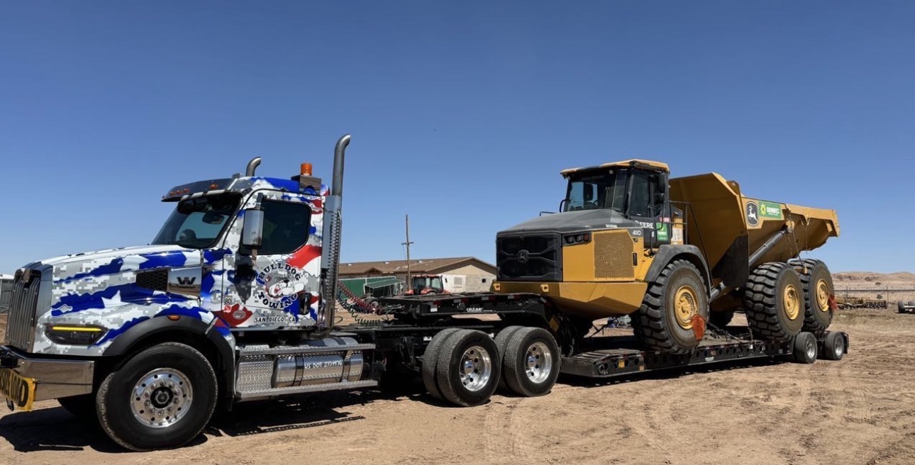 Bulldog Towing transporting heavy equipment through rural terrain using specialized hauling equipment.